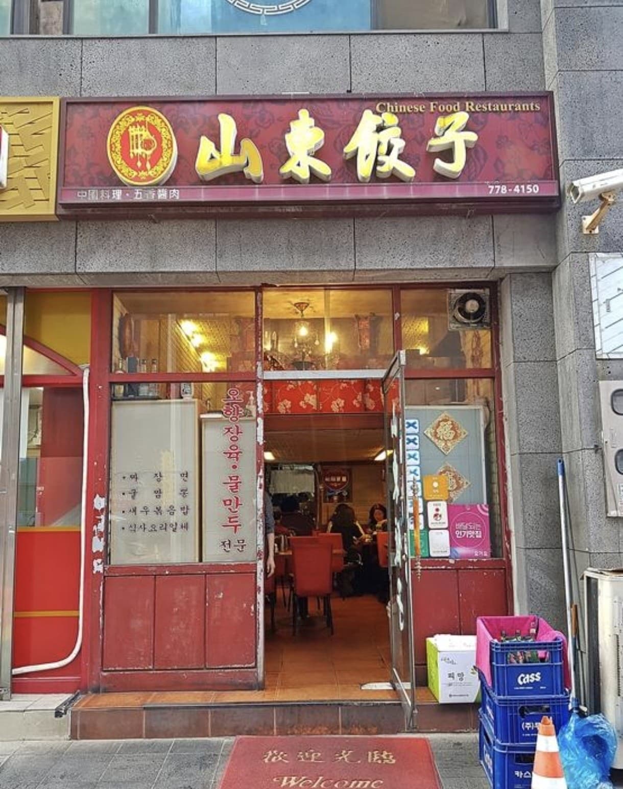 The red-and-gold storefront of Sandong Gyoja Korean-Chinese restaurant with its Chinese characters sign and open doorway