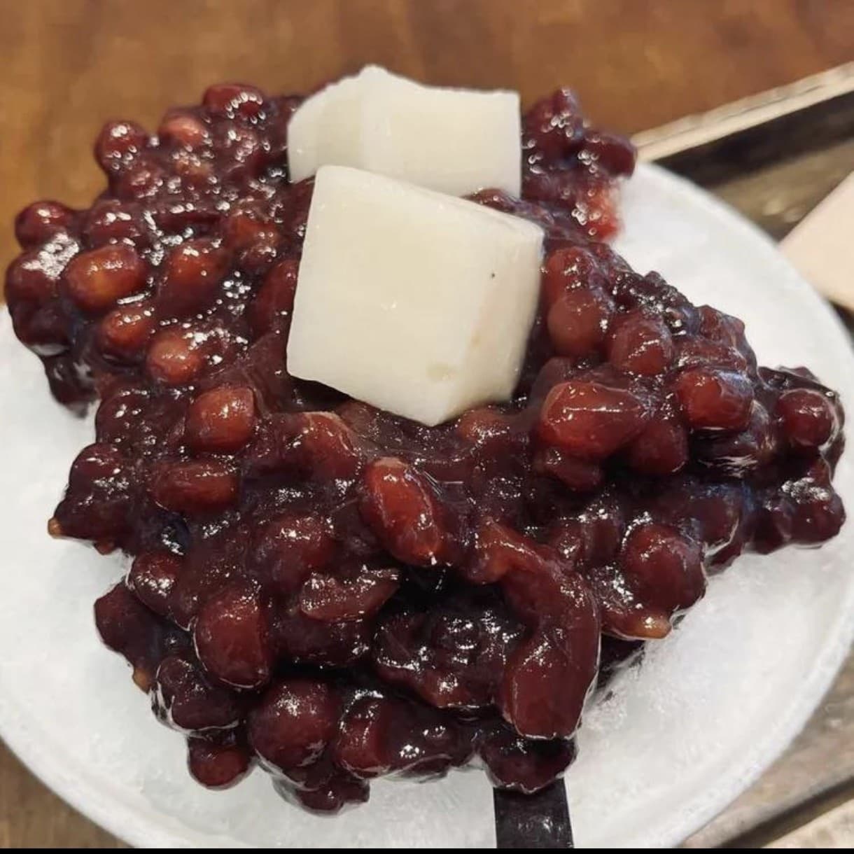 A plate of Tongui-dong Danpat sweet red beans topped with two white rice-cake cubes