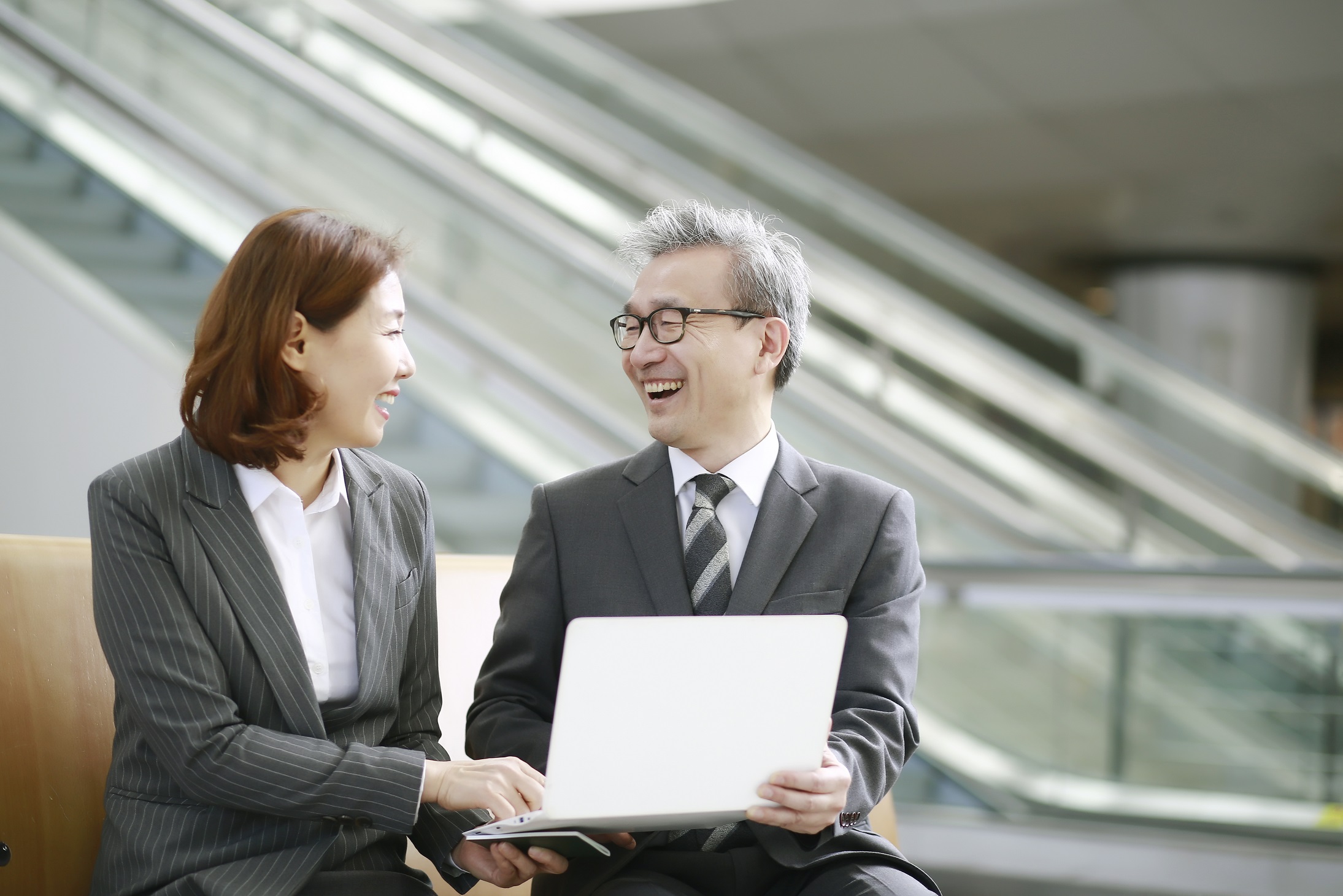 Two business professionals smiling together over a laptop